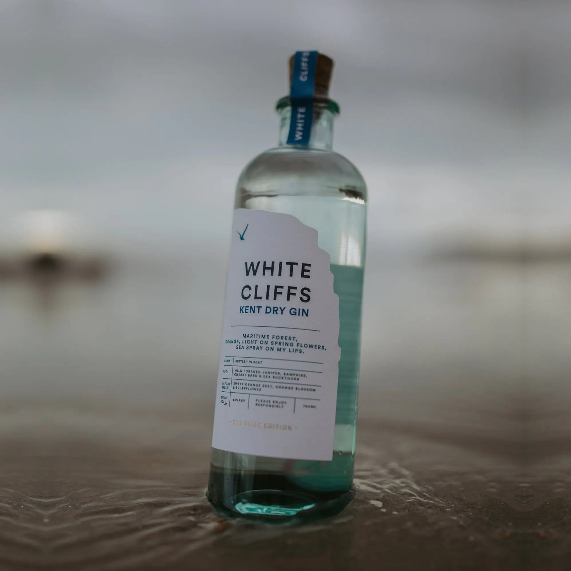 Bottle of White Cliffs Gin by Pleasant Land Distillery with coastal botanical design on the English seaside